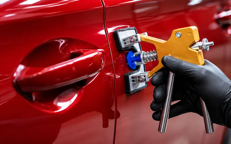 Dent repair tool on a red car door